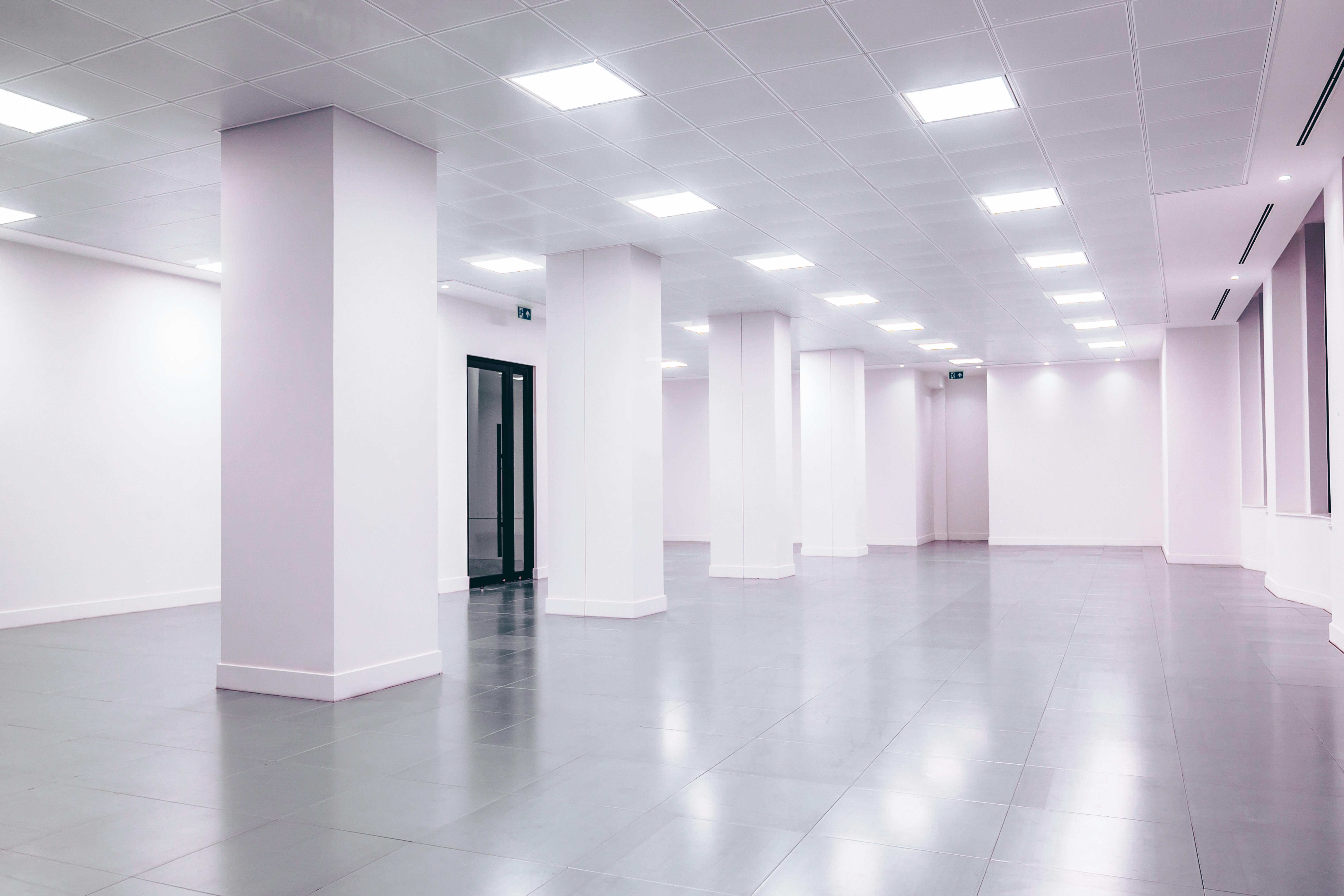 Wide-angle view of a modern minimalist white office space with clean lines and ample lighting.