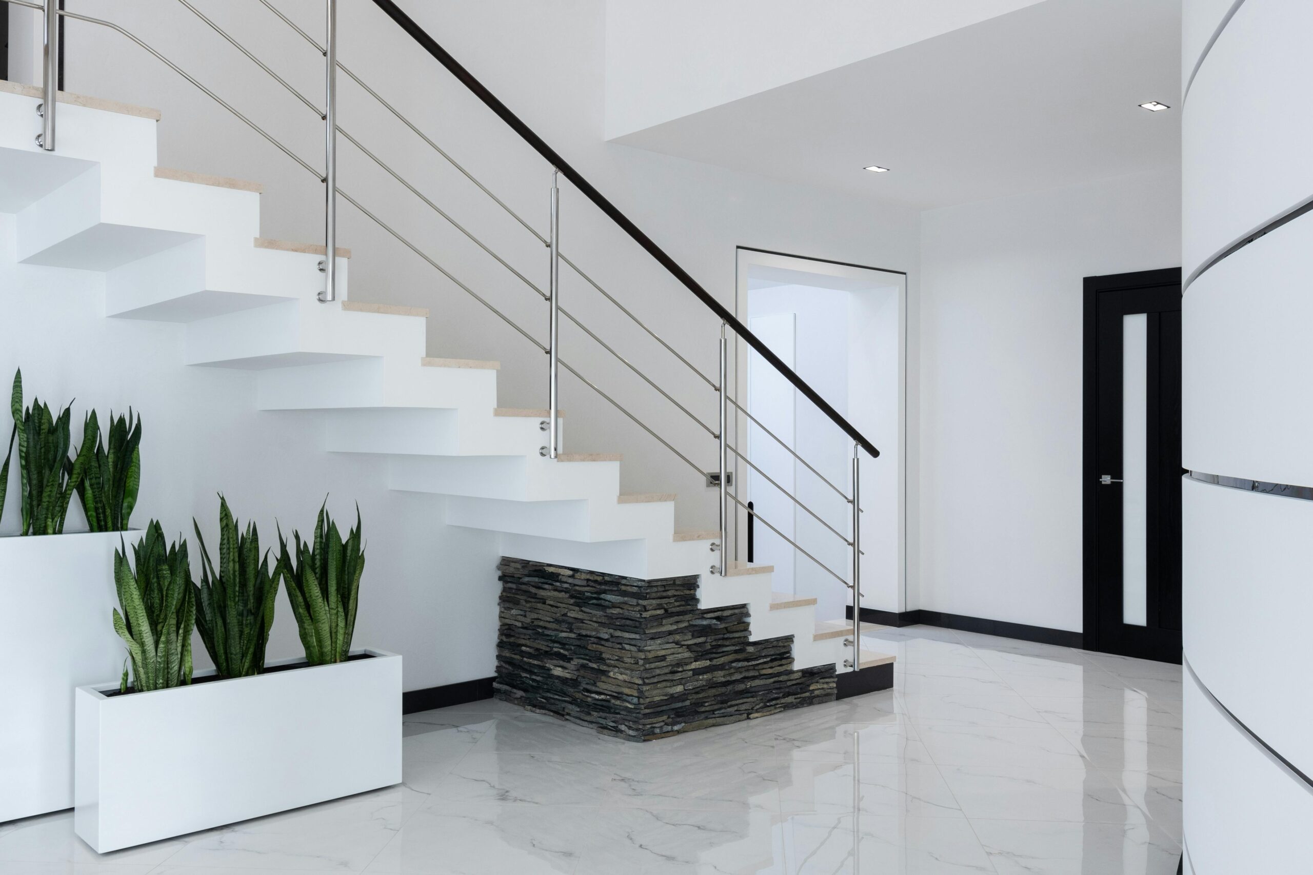Fresh green plants growing in minimalist white pots placed near staircase in modern spacious villa
