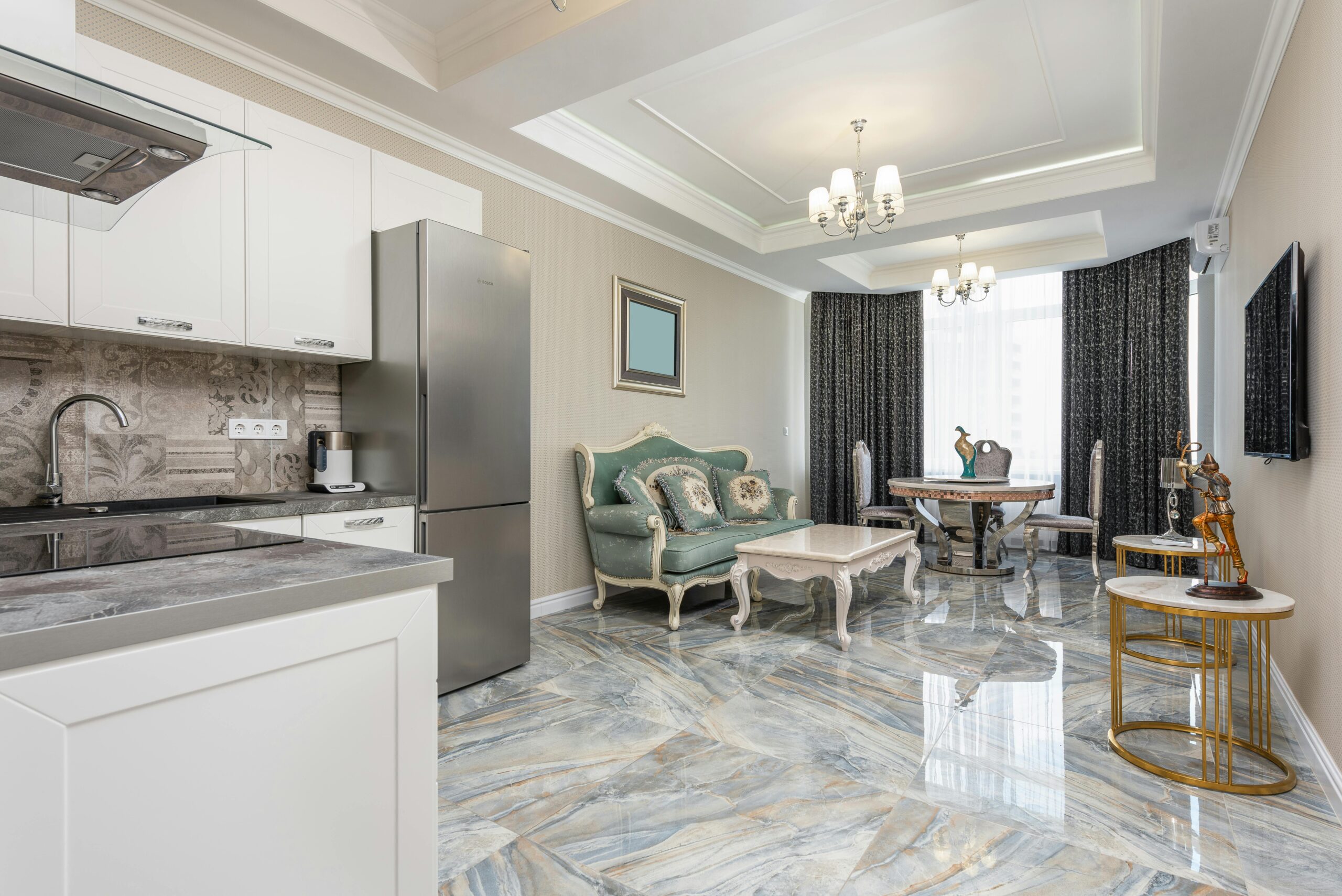 Classic living room and modern kitchen interior with tables against couch and refrigerator on marble floor at home